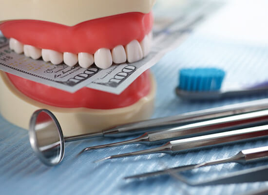 dentures with money in the teeth and dental instruments