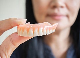 Woman holding a full denture in Kingwood, TX