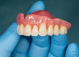 Close-up of gloved hand holding dentures in Kingwood, TX