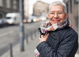 Senior woman with scarf smiling on street